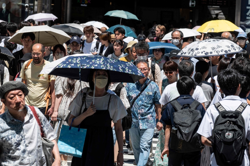 (File photo) taken on July 30, 2023 shows people using umbrellas and parasols to seek relief from the heat while walking outside Shinjuku station, as temperatures of 35C-plus (95F) have scorched the Japanese capital Tokyo for weeks. Photo by Richard A. Brooks / AFP

