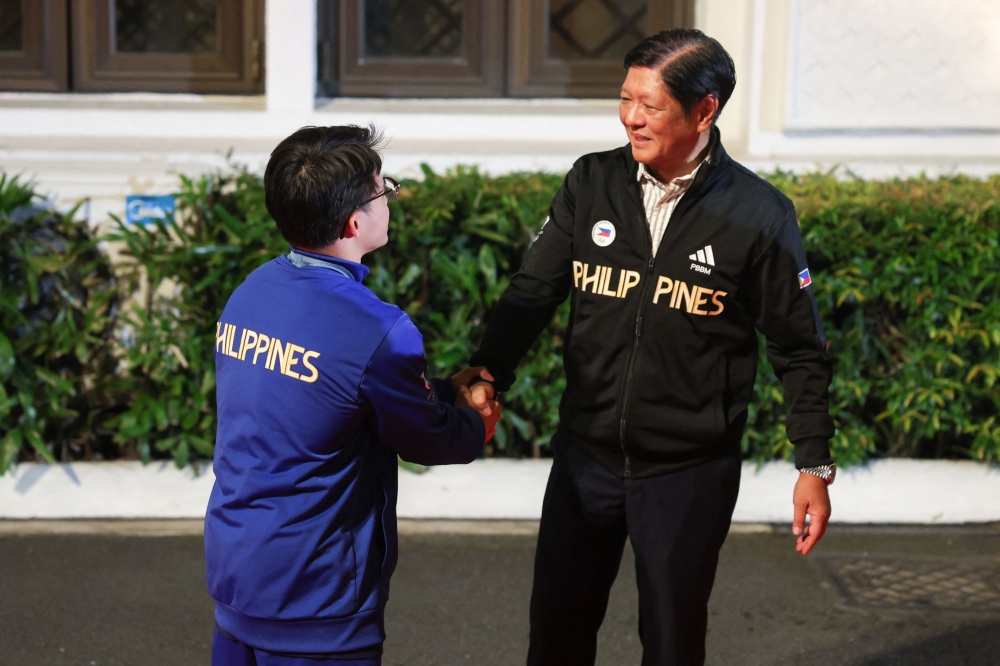 Philippines' Carlos Yulo (L), Paris 2024 Olympic Games double gold medalist in gymnastics shakes hands with President Ferdinand Marcos Jr. upon his arrival at the Malacanang presidential palace in Manila on August 13, 2024. (Photo by Basilio H SEPE / POOL / AFP)

