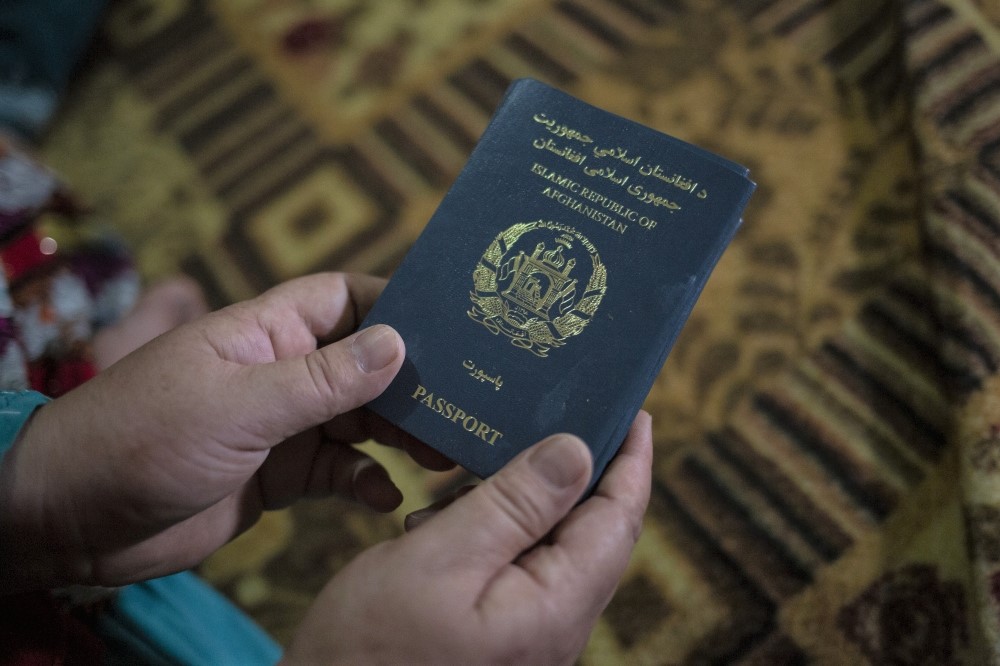 A woman holds an Afghan passport in Islamabad, Pakistan, in 2023. (Photo by Saiyna Bashir for The Washington Post)

