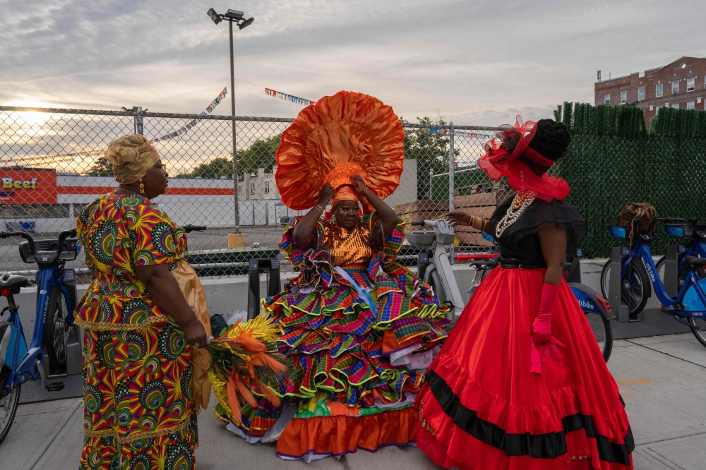 Three people take a break during the annual street party J'ouvert on September 2, 2024 in New York City. (Photo by Adam Gray / GETTY IMAGES NORTH AMERICA / Getty Images via AFP)
