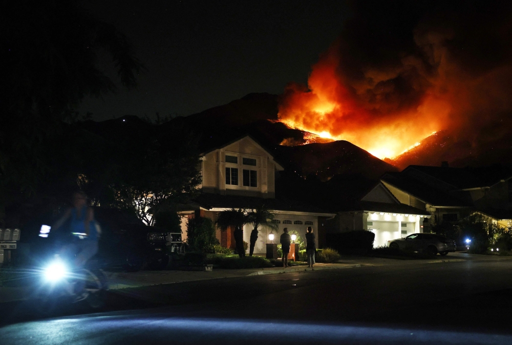 People watch (C) the Airport Fire burning on a hill above homes on September 9, 2024 in Trabuco Canyon, California. Pictures: Mario Tama/Getty Images/AFP 