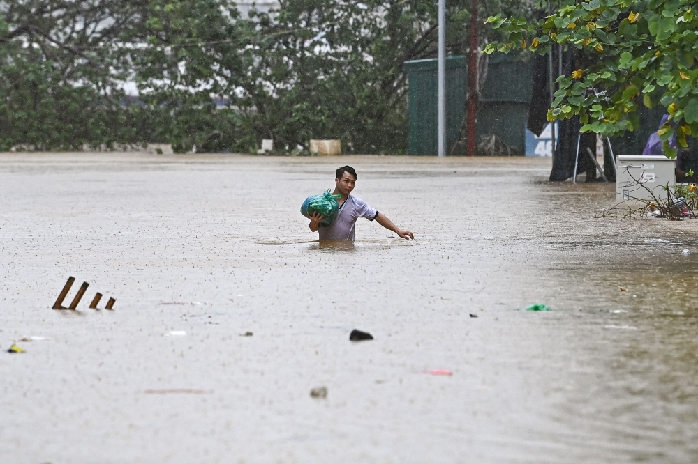 A man walks through flood waters in Hanoi on September 11, 2024, in the aftermath of Typhoon Yagi hitting northern Vietnam. (Photo by NHAC NGUYEN / AFP)
 