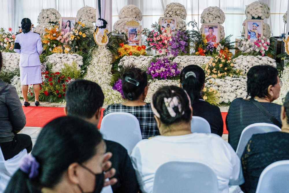Mourners gather before prayers for the victims of a school bus fire near their coffins at Wat Khao Phraya Sangkharam School in Uthai Thani on October 3, 2024. Photo by Chanakarn Laosarakham / AFP