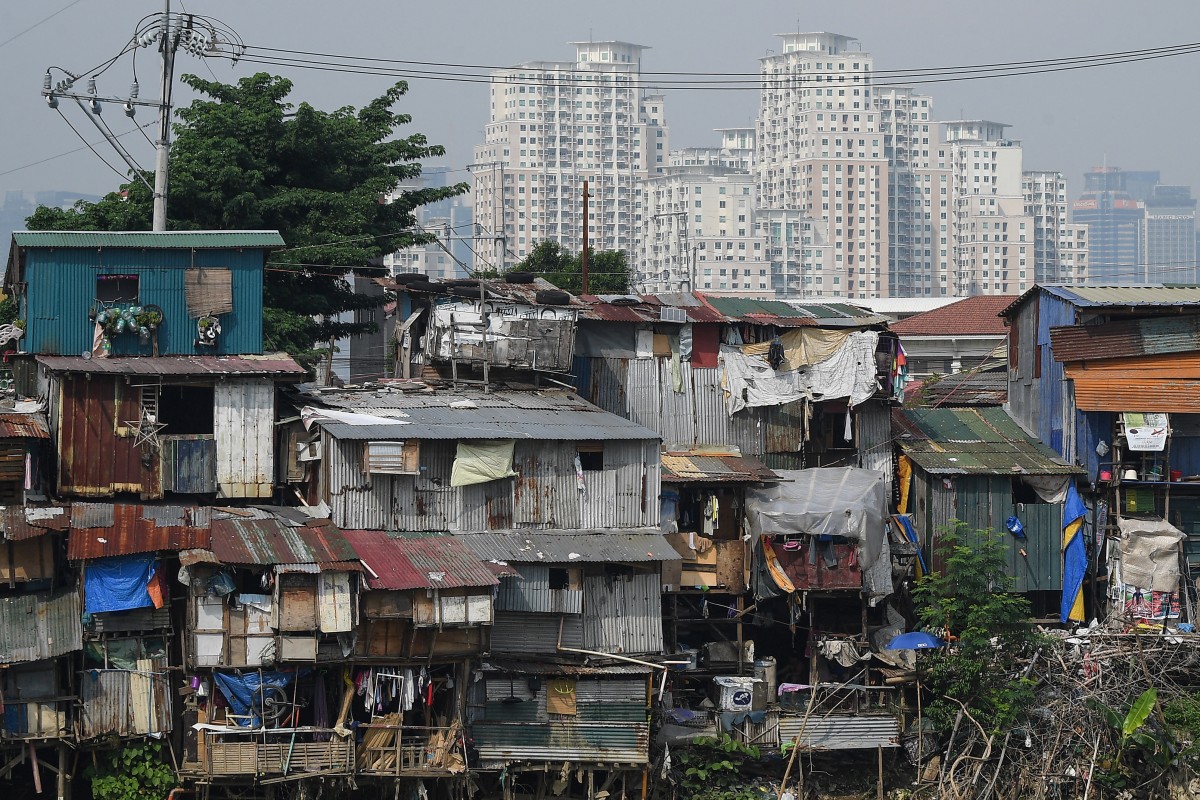 This picture shows shanty homes along a floodway before high rise buildings in Manila on October 4, 2024. (Photo by Ted ALJIBE / AFP)
