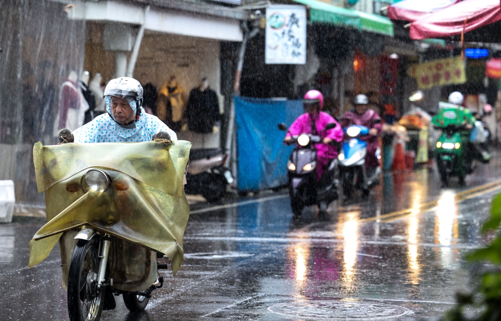People ride scooters in heavy rain as Typhoon Kong-rey approaches Taiwan, in Yilan County on October 30, 2024. (Photo by I-Hwa CHENG / AFP)