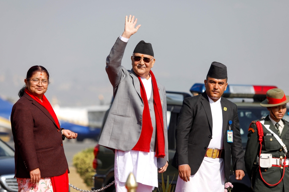 Nepal's prime minister Khadga Prasad Sharma Oli waves alongside his wife Radhika Shakya before his departure, at the Tribhuvan International airport in Kathmandu on December 2, 2024. (Photo by Aryan Dhimal / AFP)