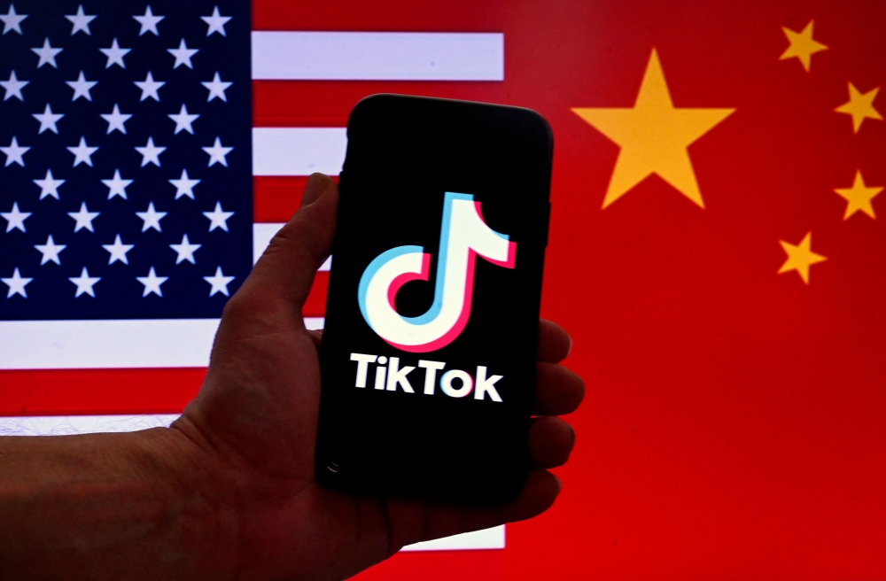 File: In this photo illustration the social media application logo for TikTok is displayed on the screen of an iPhone in front of a US flag and Chinese flag background in Washington, DC, on March 16, 2023. (Photo by Olivier Douliery / AFP)
