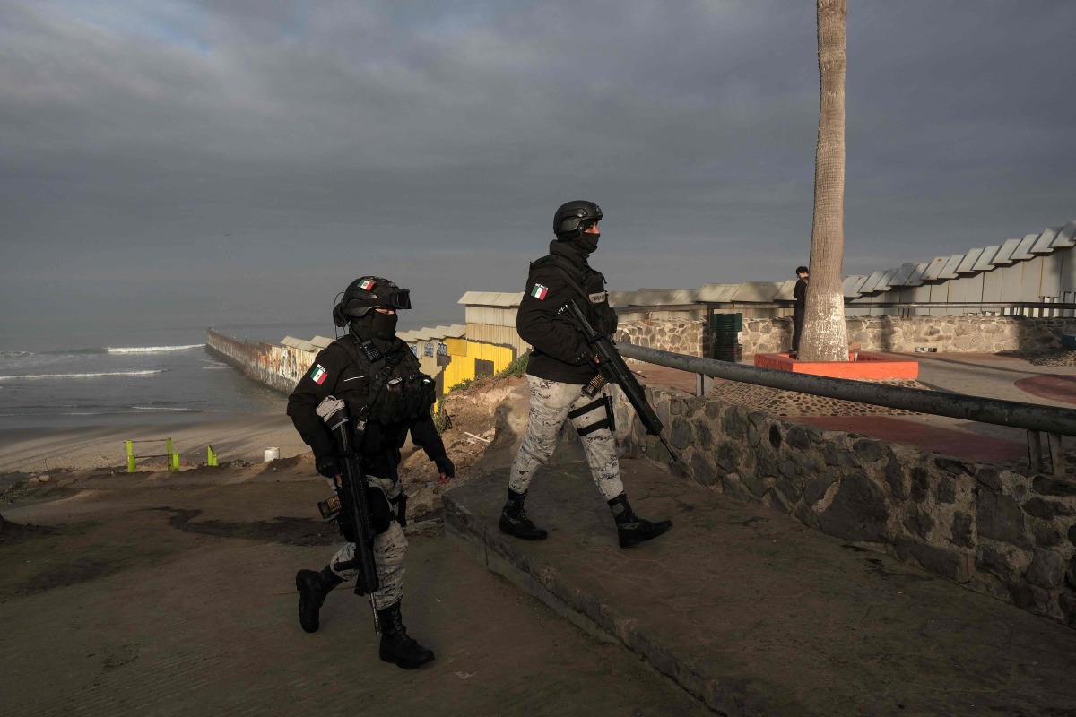 Mexico's National Guard officers, part of the Operation Frontera Norte, stand guard next to the Mexico-US border wall in Playas de Tijuana, Baja California state, Mexico on February 5, 2025. (Photo by Guillermo Arias / AFP)

