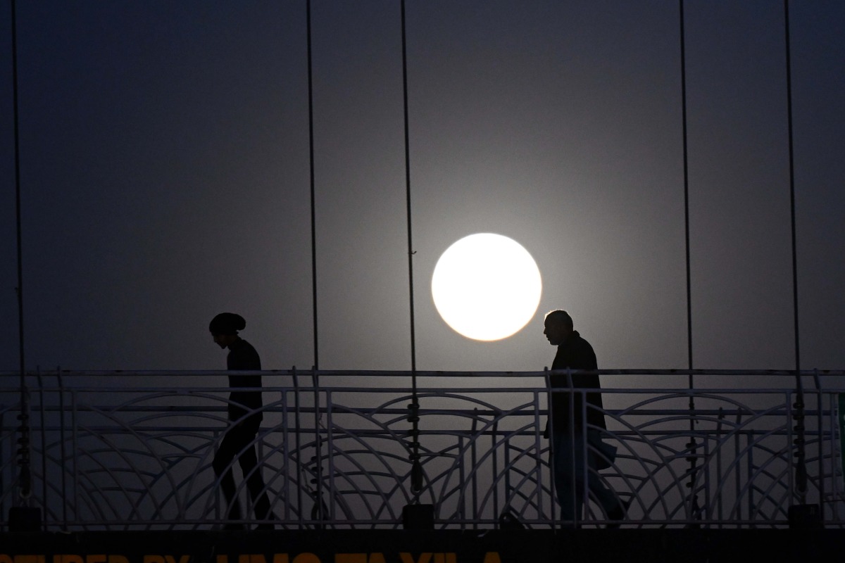 People walk on a bridge as a full moon is seen over Islamabad, Pakistan, on Feb. 12, 2025. (Xinhua/Ahmad Kamal)
