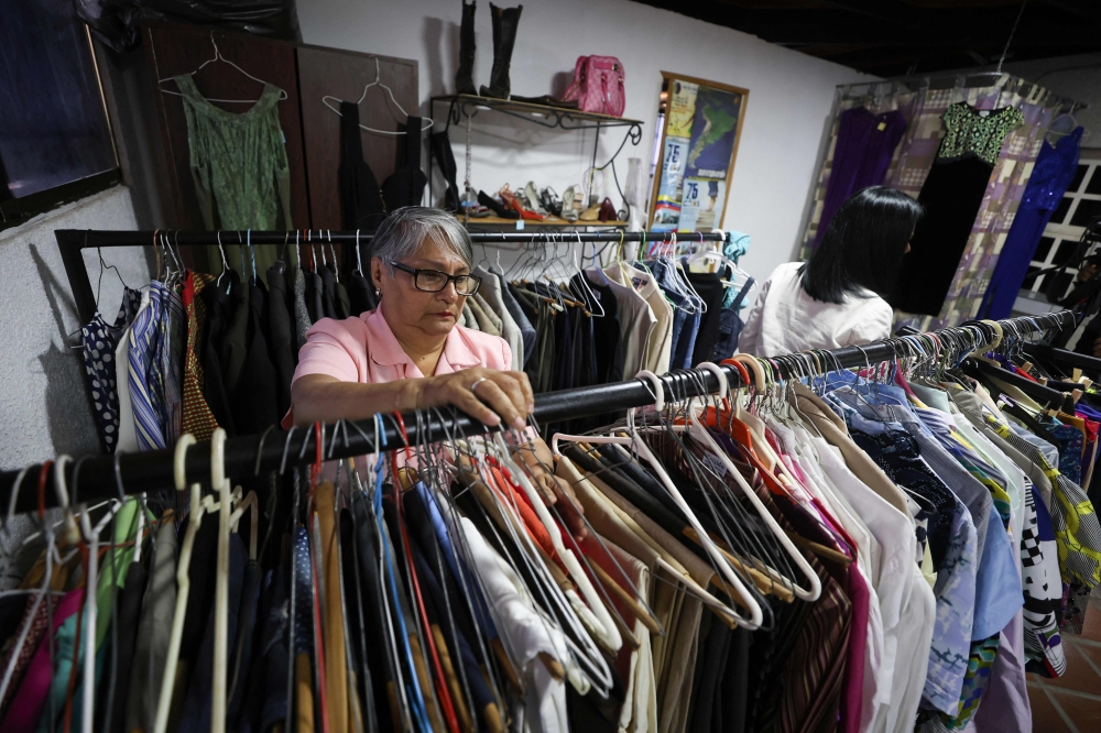 A teacher browses clothes inside a second-hand run by the Venezuelan Teachers' Federation (FVM) in Caracas, on February 17, 2025. (Photo by Pedro Mattey / AFP)
 