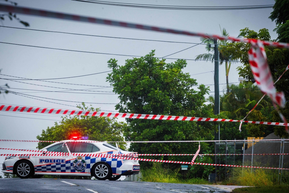 Police cordons are displayed to stop traffic after power lines fell across a road in Coorparoo in Brisbane on March 8, 2025, as cyclone Alfred crossed the southeast Queensland coast. (Photo by Patrick Hamilton / AFP)