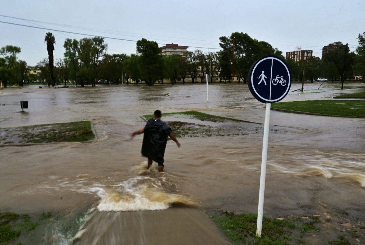 A man crosses flooded waters after a powerful storm struck the city of Bahia Blanca, 600 km south of Argentina's capital, on March 7, 2025. (Photo by PABLO PRESTI / AFP)
