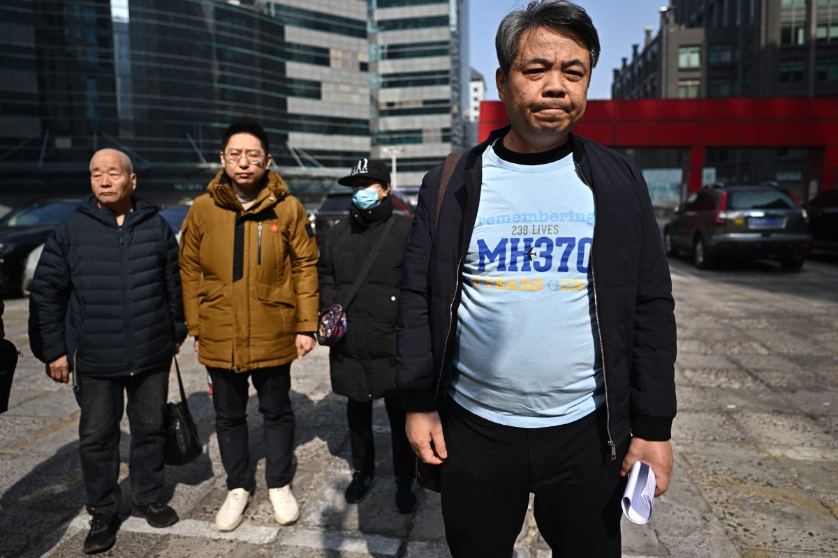 Jiang Hui (R), a relative of a passenger on board the missing Malaysia Airlines flight MH370, stands with others with missing loved ones as he speaks to the media after a meeting in Beijing on March 8, 2025, on the 11th anniversary of the flight's disappearance. (Photo by Pedro Pardo / AFP)
