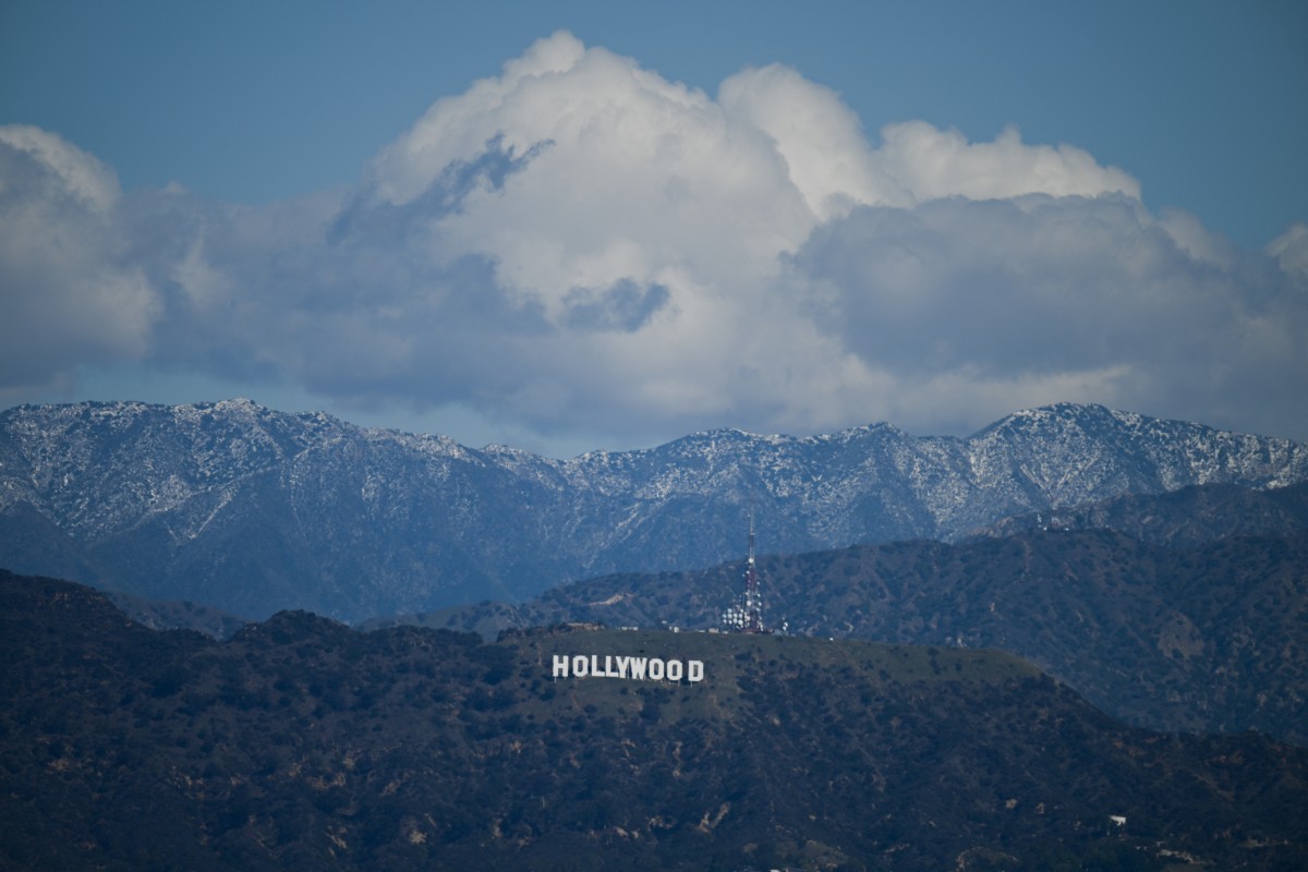 Snow dusted mountains stand on the skyline behind a view of the Hollywood sign following rain storms, as seen from the Kenneth Hahn State Recreation Area, in Los Angeles, California on March 7, 2025. (Photo by Patrick T. Fallon / AFP)
