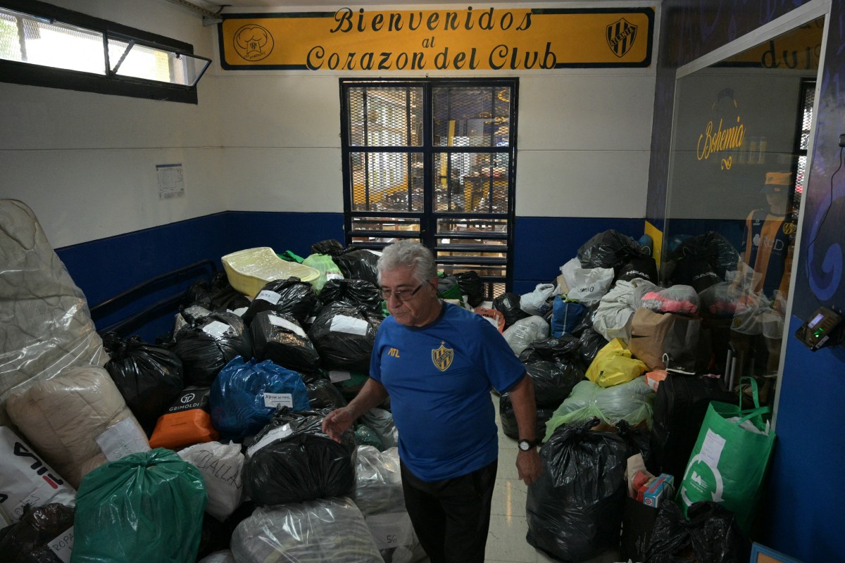 A man walks among donations for people affected by severe flooding in Bahia Blanca, at Club Atletico Atlanta in Buenos Aires on March 10, 2025. (Photo by JUAN MABROMATA / AFP)
