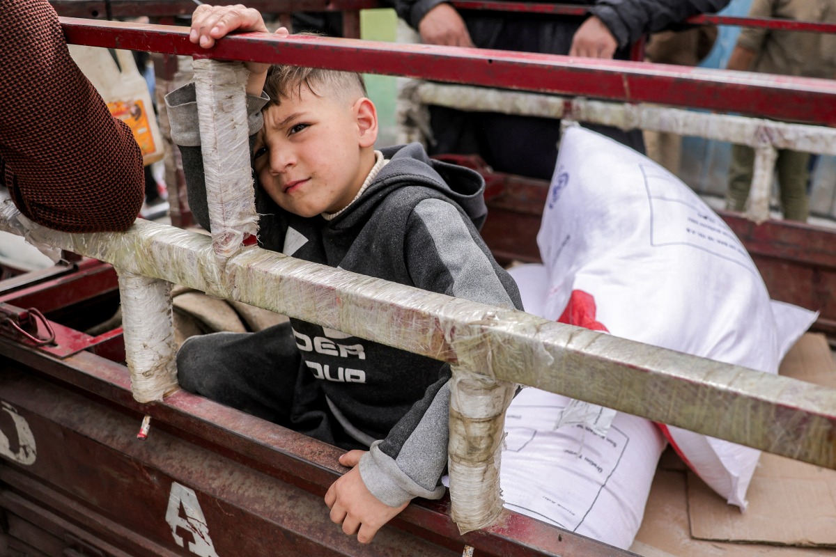 A boy sits in the back of a tricycle cart with sacks of flour provided by the Turkish disaster relief agency AFAD, received from a supply centre affiliated with the United Nations Relief and Works Agency for Palestine refugees (UNRWA) in al-Tifah neighbourhood of Gaza City on April 1, 2025. Photo by Bashar TALEB / AFP
