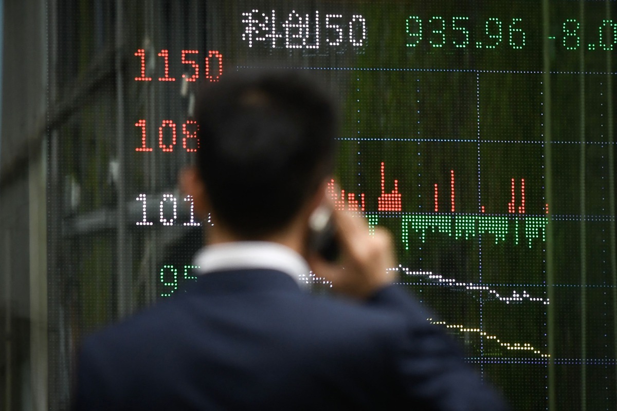 A man looks at a screen showing Chinese stock market movements as he uses his mobile phone in Beijing on April 7, 2025. (Photo by WANG Zhao / AFP)
