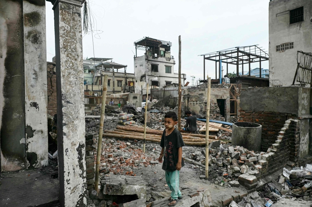 A boy stands among the debris of buildings damaged in a fire in Mandalay on April 11, 2025, following the devastating March 28 earthquake. (Photo by Sai Aung Main / AFP)
