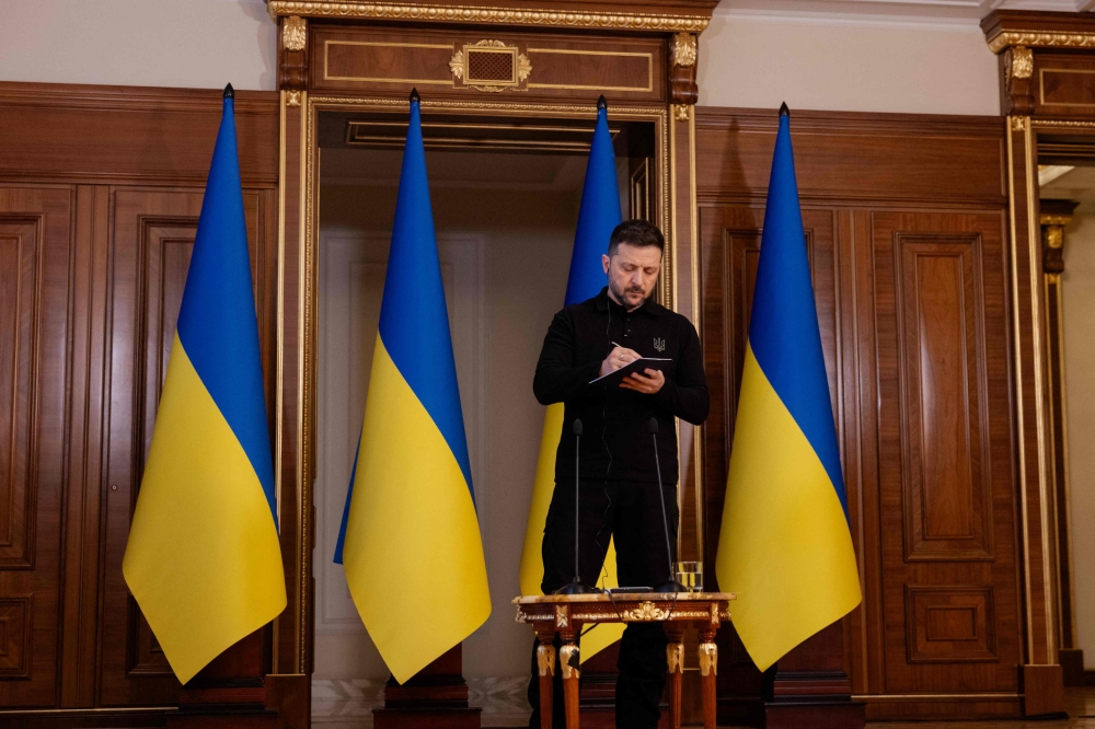 Ukraine's President Volodymyr Zelensky takes notes during a press conference in Kyiv on April 17, 2025, amid the Russian invasion of Ukraine. (Photo by Tetiana Dzhafarova / AFP)