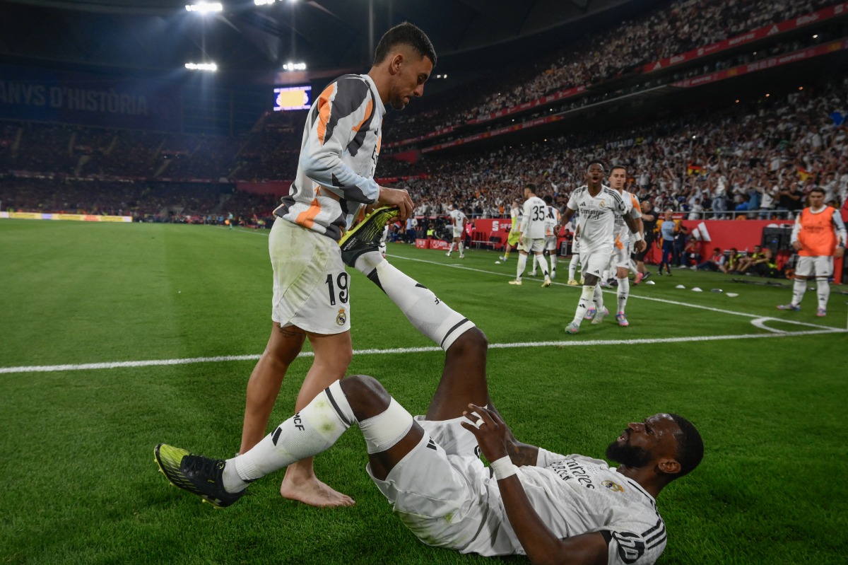 Real Madrid's Spanish midfielder #19 Dani Ceballos helps Real Madrid's German defender #22 Antonio Ruediger during their Spanish Cup, Copa del Rey (King's Cup) final football match between FC Barcelona and Real Madrid CF at La Cartuja stadium in Seville on April 26, 2025. (Photo by Josep LAGO / AFP)