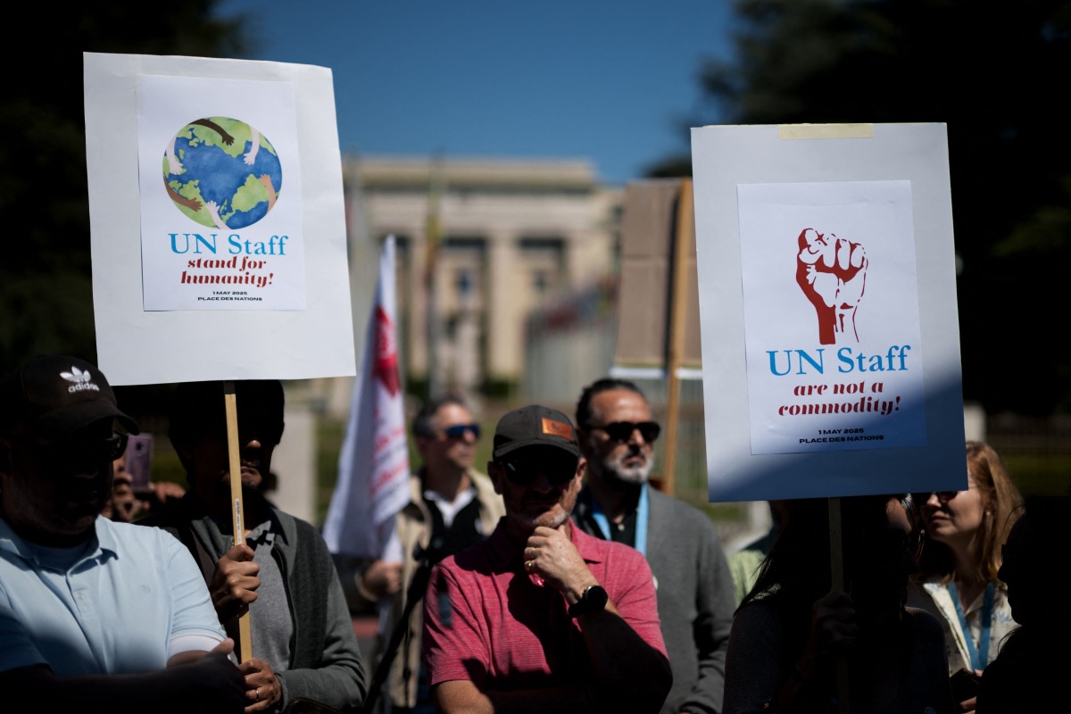 Geneva based United Nations employees hold slogans during a demonstration in Geneva, on May 1, 2025, over deep funding cuts, especially from key donor the United States, which have led to mass-layoffs and threatened life-saving services around the world. (Photo by Fabrice COFFRINI / AFP)
