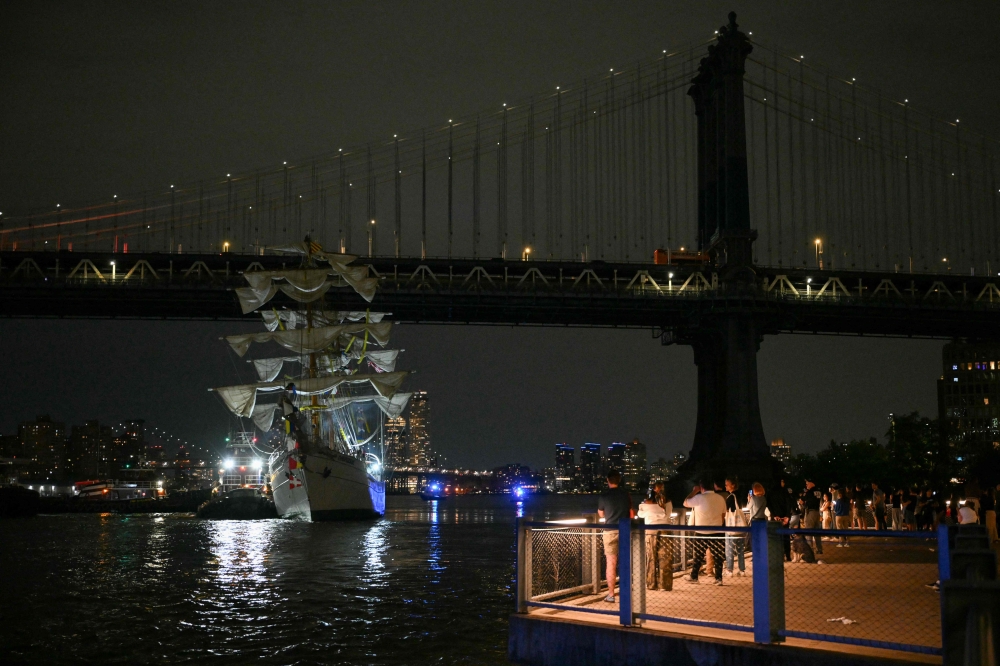 People gather to look at a Mexican Navy training ship near the Manhattan Bridge after it slammed into the nearby Brooklyn Bridge in New York on May 17, 2025. (Photo by Angela Weiss / AFPTV / AFP)