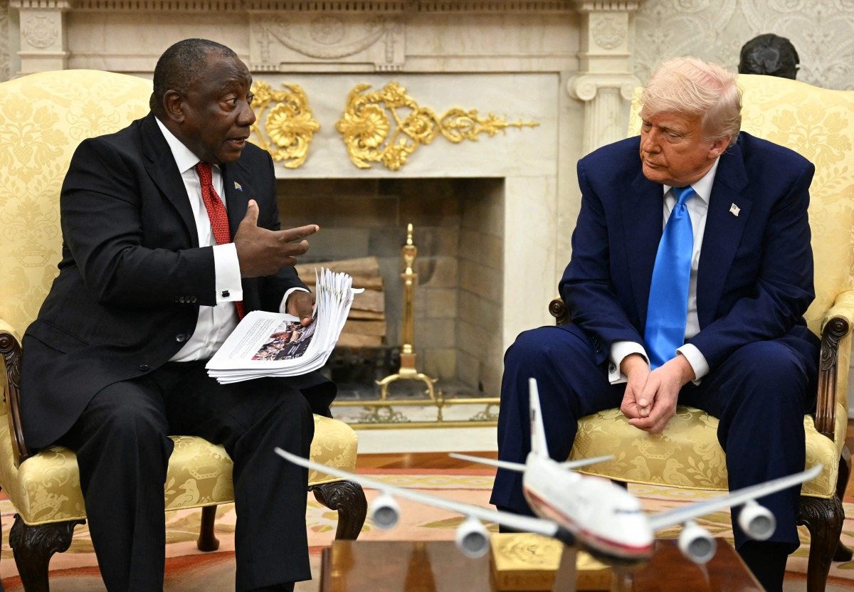 US President Donald Trump hands papers to South African President Cyril Ramaphosa during a meeting in the Oval Office of the White House in Washington, DC, on May 21, 2025. (Photo by Jim WATSON / AFP)
