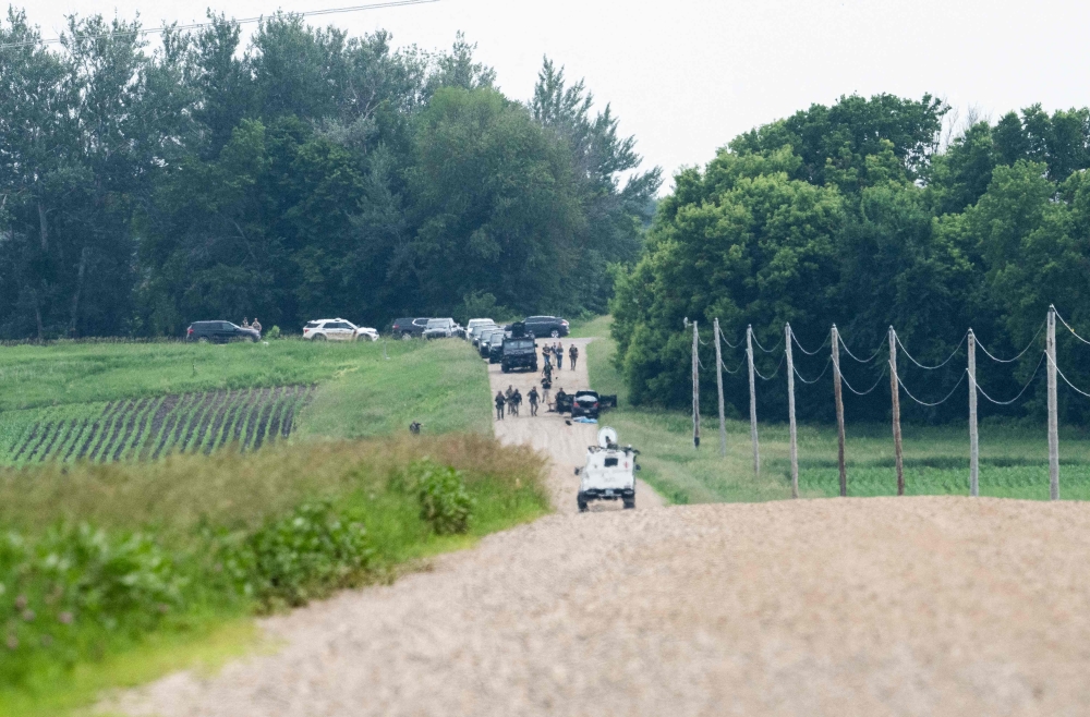 Law enforcement search the area around a vehicle on 301st Avenue on June 15, 2025 in Belle Plaine, Minnesota. Stephen Maturen/Getty Images/AFP 
 