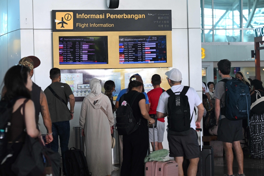 Passengers look at electronic boards displaying cancelled flights at the Ngurah Rai International Airport in Tuban near Denpasar on June 18, 2025. Sonny Tumbelaka /AFP. 