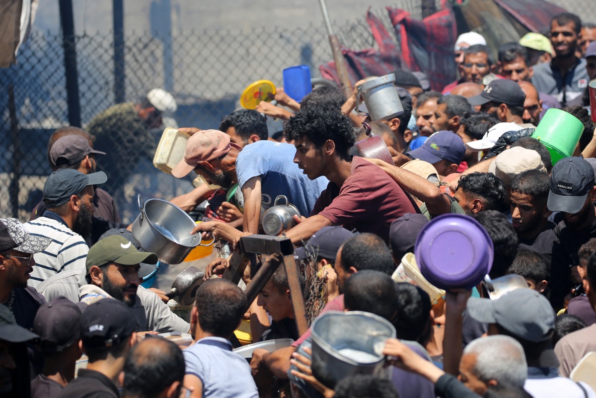 Palestinians gather at a food distribution point in the Nuseirat refugee camp in the central Gaza Strip on July 19, 2025. (Photo by Eyad BABA / AFP)