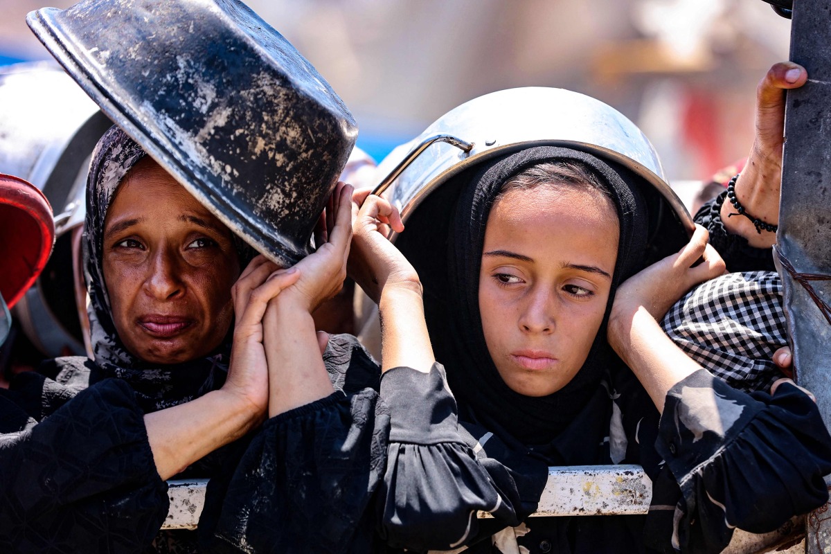 Palestinians wait at a lentil soup distribution point in Gaza City in the northern Gaza Strip on July 27, 2025. (Photo by Omar AL-QATTAA / AFP)
