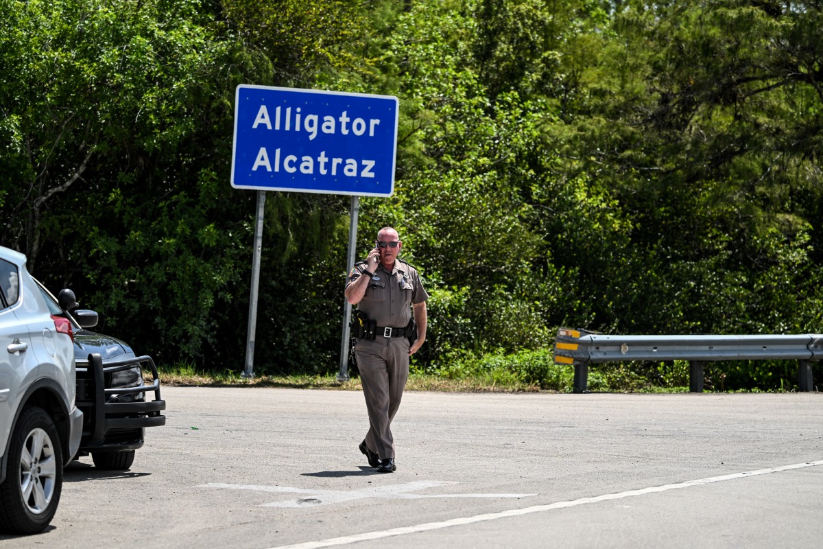 A Florida Highway Patrol officer looks on as protesters gather to demand the closure of the immigrant detention center known as 