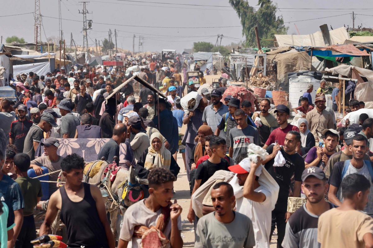 Palestinians carry humanitarian aid they received at the Rafah corridor as they walk in the Mawasi area of Rafah in the southern Gaza Strip yesterday. (AFP)