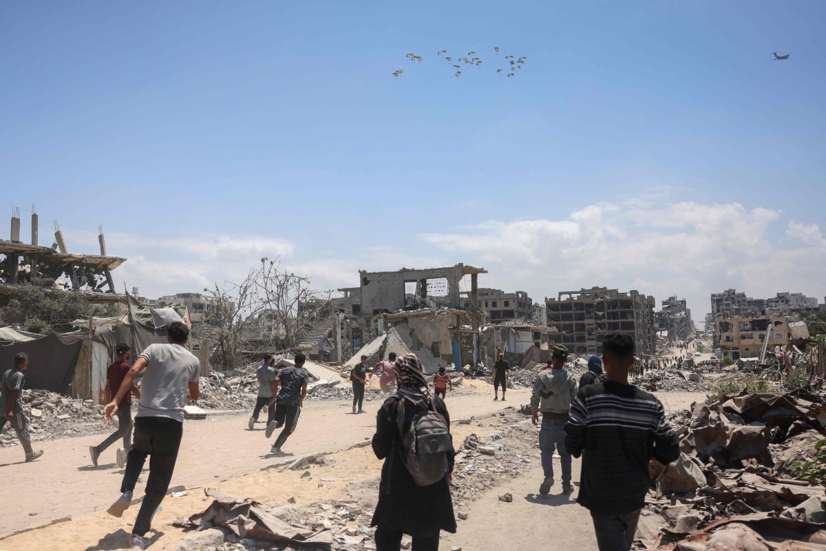 Palestinians in Jabalia in the northern Gaza Strip rush towards a plane conducting an airdrop of aid above the Palestinian territory on August 1, 2025. Photo by Bashar TALEB / AFP