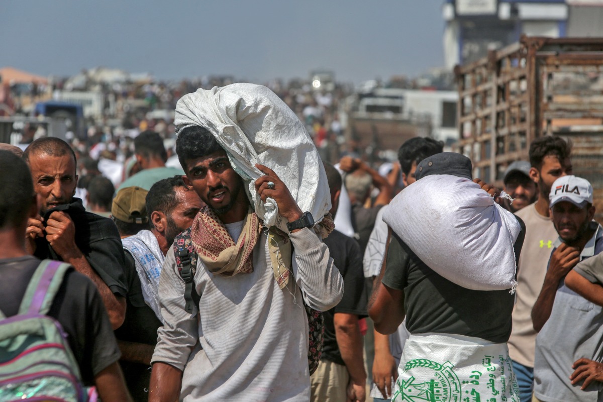 Displaced Palestinians carry food parcels as they raid trucks carrying humanitarian aid in Khan Yunis, in the southern Gaza Strip on August 9, 2025. Photo by AFP