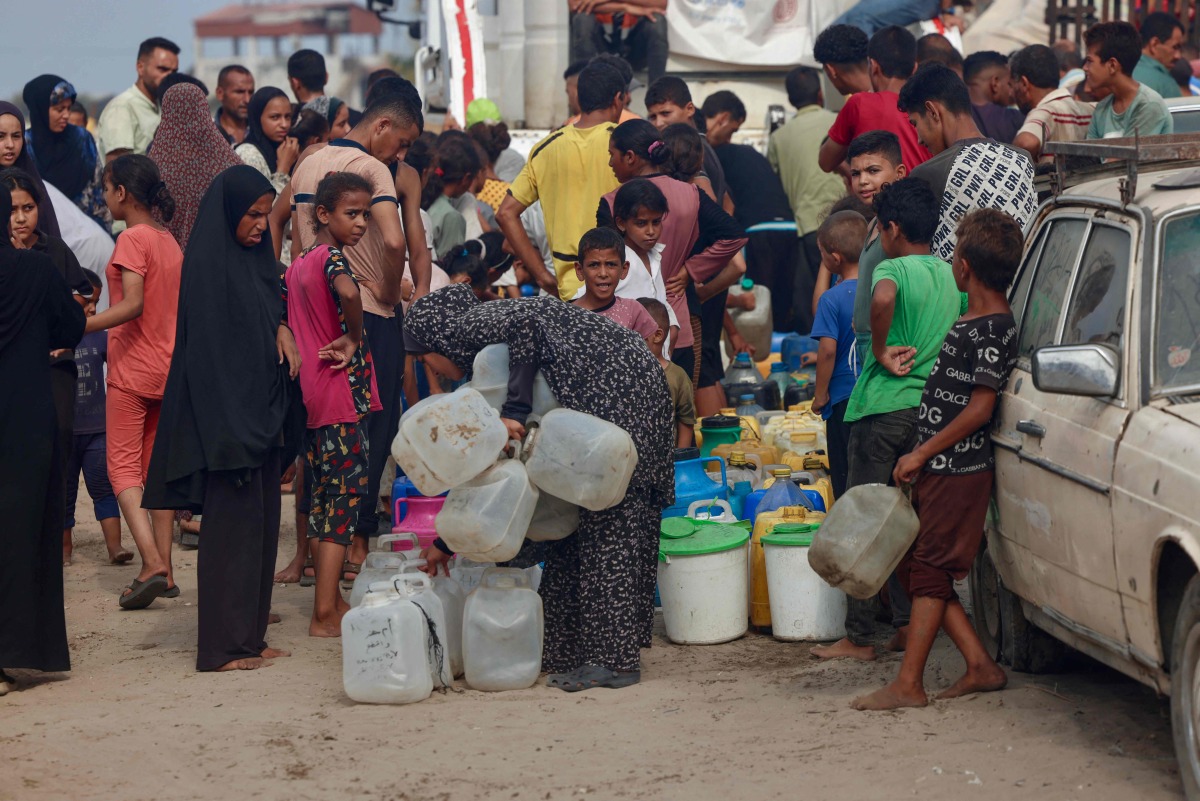 Palestinians queue to fill up on drinking water in the sweltering heat in the Mawasi area of Khan Yunis in the southern Gaza Strip on August 12, 2025. (Photo by AFP)
