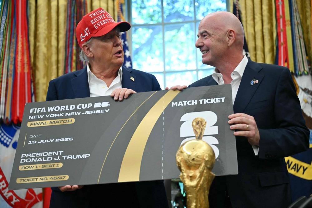 FIFA president Gianni Infantino presents US President Donald Trump a FIFA World Cup ticket for the final match in the Oval Office of the White House in Washington, DC, on August 22, 2025. (Photo by Andrew Caballero-Reynolds / AFP)
