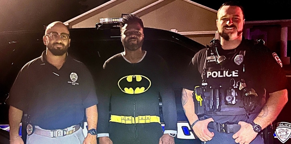 Kyle Myvett, center, poses with police officers in his Batman pajamas after detaining a burglary suspect in Cape Coral, Florida, early Wednesday morning. Cape Coral Police Department