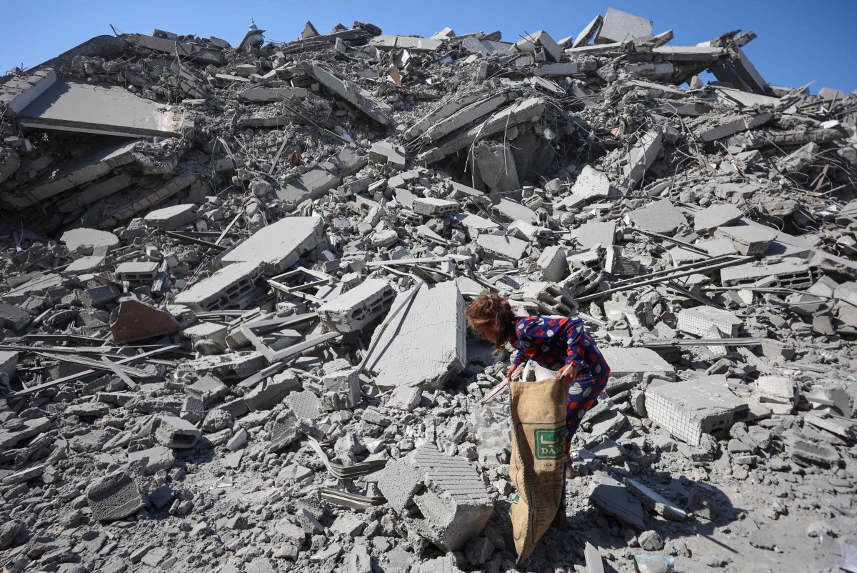 A Palestinian girl searches the rubble of al-Ghafari tower after its destruction by Israeli airstrikes in Gaza City on September 15, 2025. (Photo by Omar AL-QATTAA / AFP)
