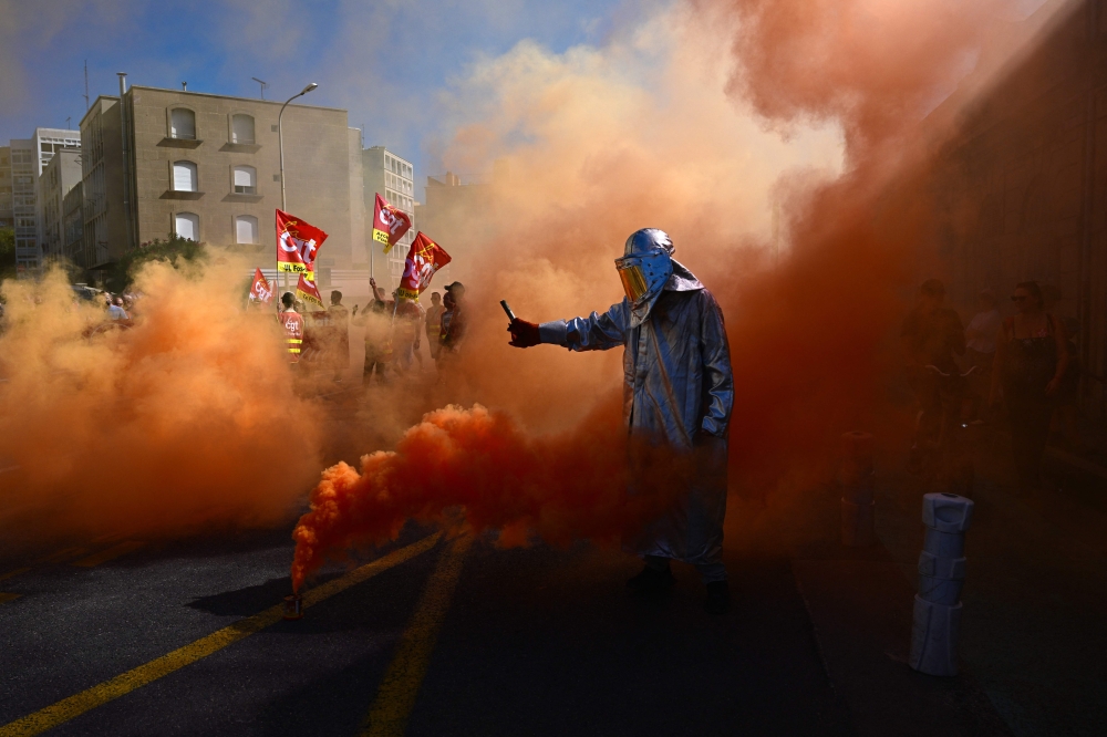 A protester lights flares in Marseille, southeastern France, on September 18, 2025, during a day of nationwide strikes and protests called by unions over France's national budget. (Photo by Miguel Medina / AFP)