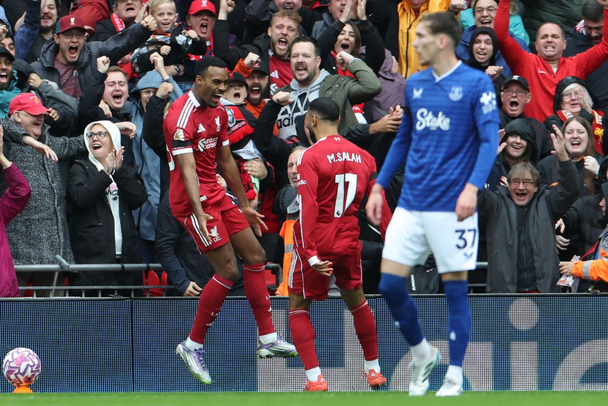 Liverpool's Dutch midfielder #38 Ryan Gravenberch (L) celebrates with Liverpool's Egyptian striker #11 Mohamed Salah (C) after scoring the opening goal of the English Premier League football match between Liverpool and Everton at Anfield in Liverpool, north west England on September 20, 2025. (Photo by Darren Staples / AFP)