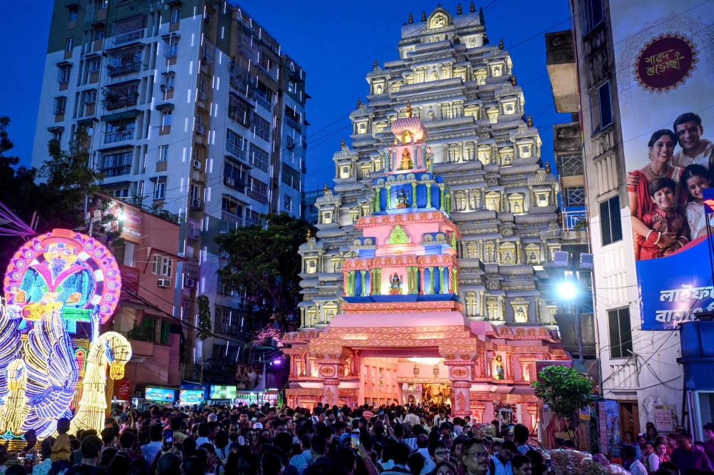 Devotees throng at the entrance during a visit to the 'Pandal' (temporary structure for worship) in Kolkata on September 27, 2025. (Photo by Dibyangshu Sarkar / AFP)