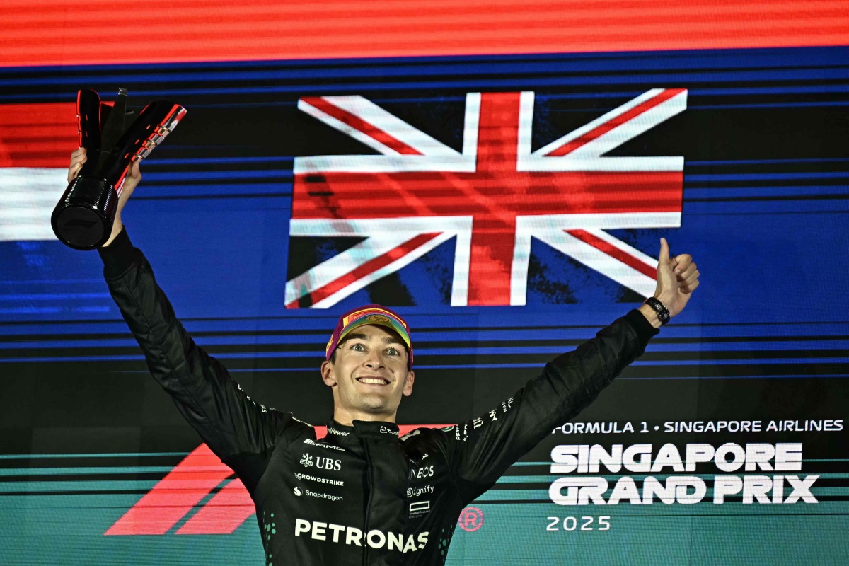 First-placed Mercedes' British driver George Russell celebrates on the podium after the Formula One Singapore Grand Prix night race at the Marina Bay Street Circuit in Singapore on October 5, 2025. (Photo by Lillian SUWANRUMPHA / AFP)