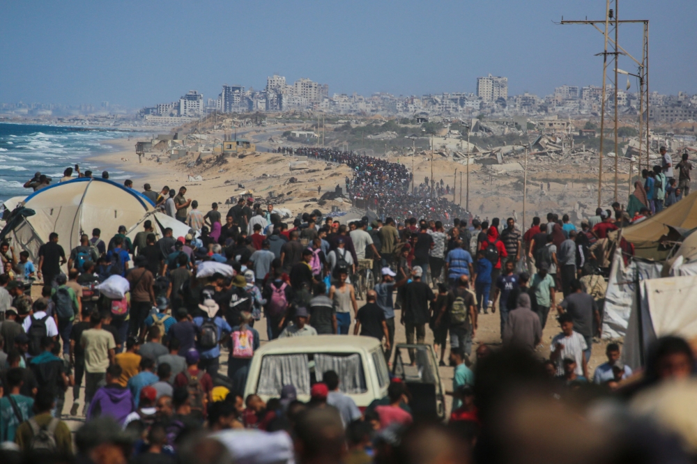 Palestinians walk along Al-Rashid road toward Gaza City from Nuseirat in the central Gaza Strip on October 10, 2025. (Photo by Bashar Taleb / AFP)