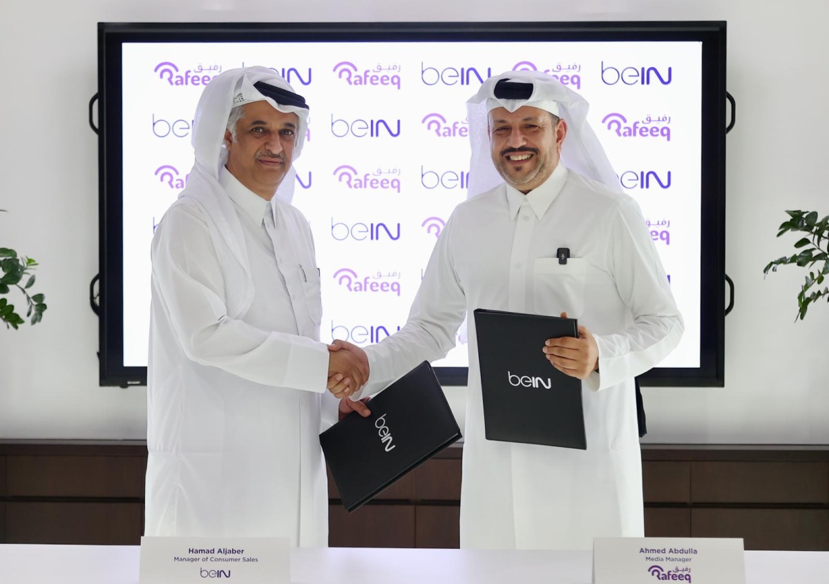beIN Consumer Sales Manager Hamad Aljaber and Rafeeq Media Manager Ahmed Abdulla exchange documents during the ceremony. 