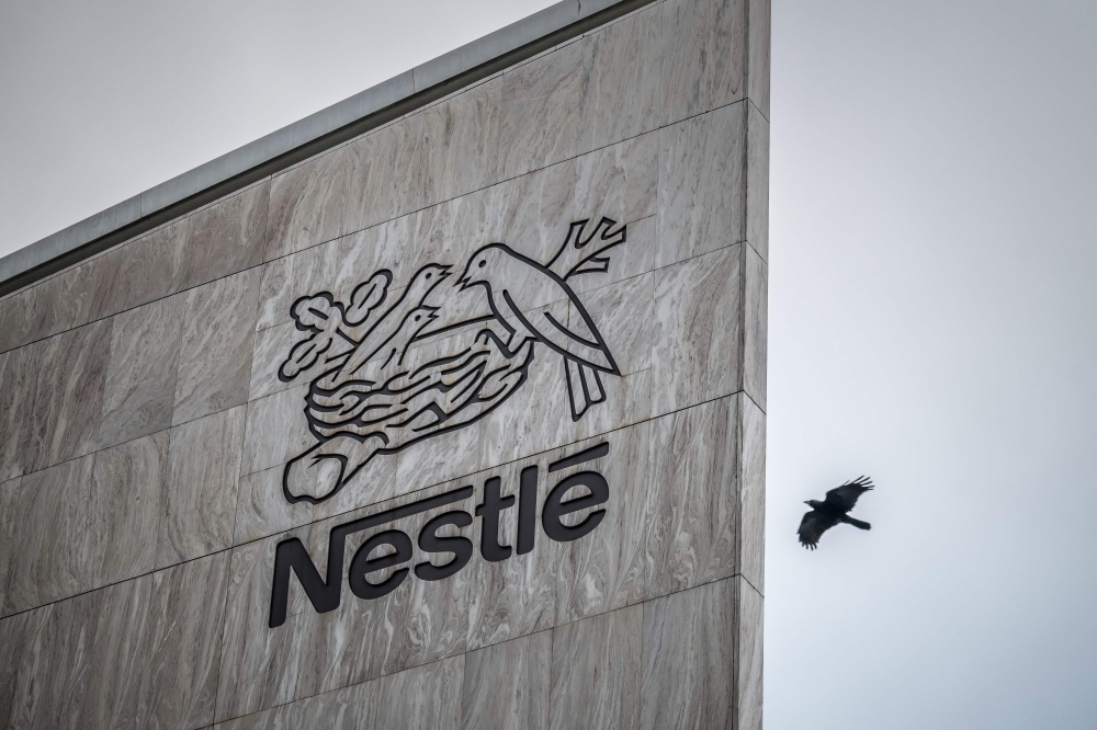 This photograph shows a bird flying next to the logo of Swiss food giant Nestle on the facade of its headquarters, in Vevey, western Switzerland, on October 14, 2025. (Photo by Fabrice Coffrini / AFP)