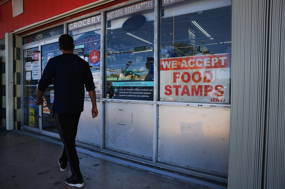 A 'We Accept Food Stamps' sign hangs in the window of a grocery store on October 31, 2025 in Miami, Florida. (Photo by Joe Raedle / Getty Images via AFP)