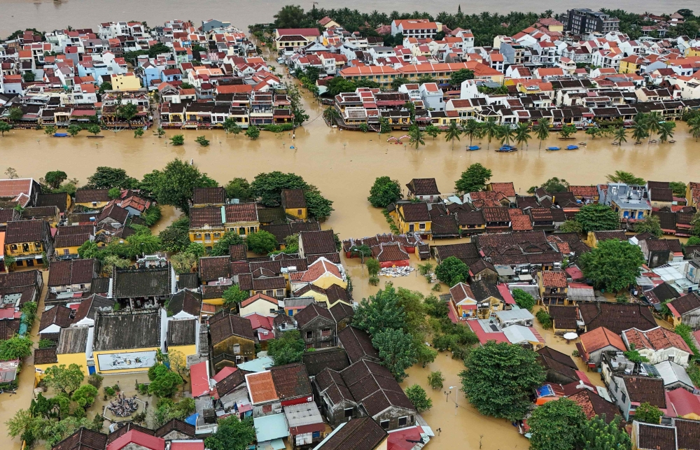 (Files) This aerial picture shows floodwaters inundating streets and buildings following heavy rains in Hoi An on October 30, 2025. (Photo by NHAC NGUYEN / AFP)
