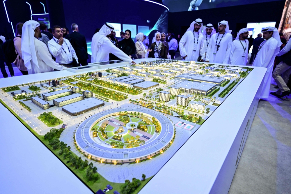 Guests look at a model of the largest data center in the UAE under construction in Abu Dhabi as the Stargate initiative, a joint venture between G42, Microsoft, and OpenAI, during the Abu Dhabi International Petroleum Exhibition & Conference (ADIPEC) in Abu Dhabi on November 3, 2025. (Photo by Giuseppe Cacace / AFP)
