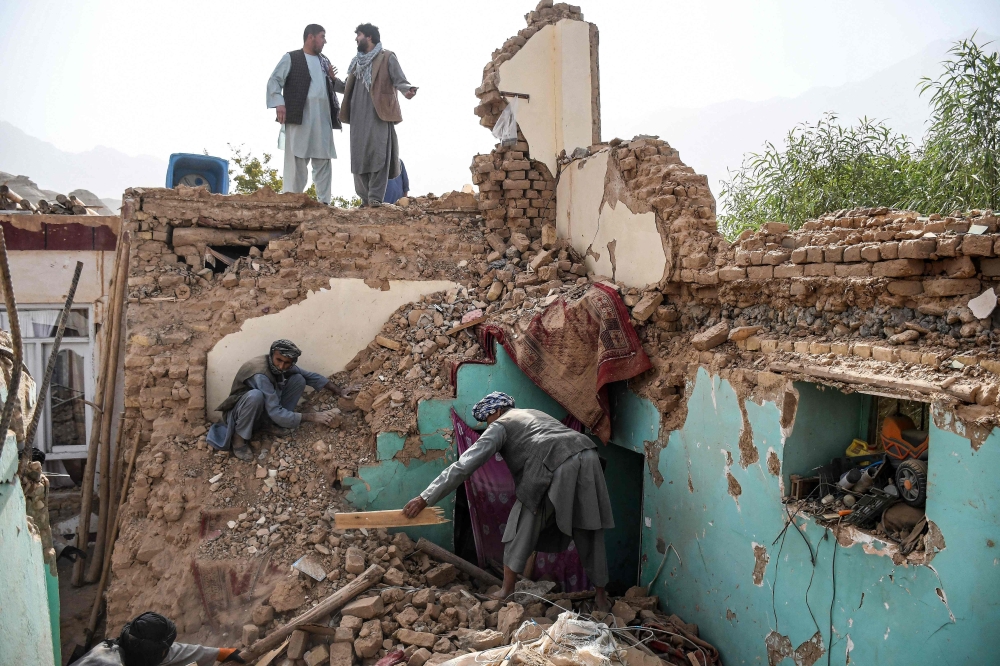 Afghan earthquake survivors search through the remains of a damaged house at a village in Tashqurghan, in the Khulm district of Samangan province on November 3, 2025. (Photo by Atif Aryan / AFP)